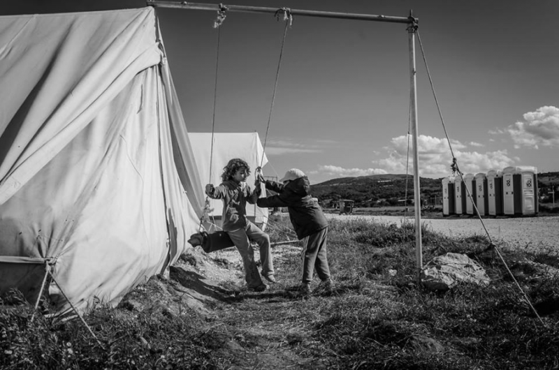 Children play on an improvised swing next to their tent in Katsikas. Photo by Cristina del Campo Martín. Used with permission.