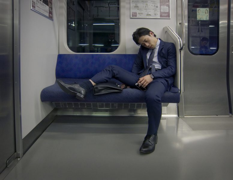 An exhausted businessman sleeping in the train.