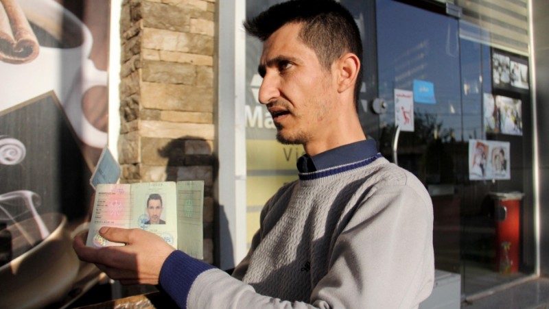 Dana Maghdeed Aziz holds up the identification issued to him by the Germany government. Credit: Rebecca Collard