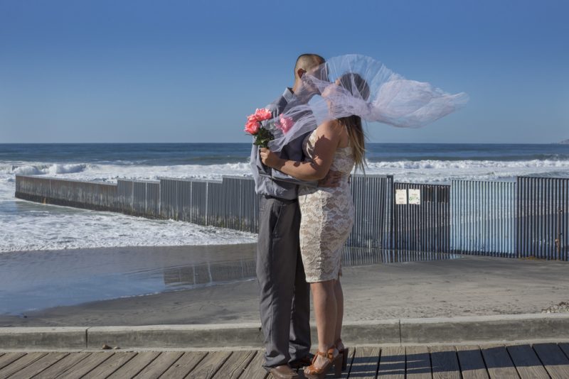 Pastor Jonathan Ibarra and wife Gladys Lopez at their wedding photoshoot in front of the the U.S.-Mexico border fence in Playas de Tijuana, Mexico, on December 12, 2015. The border is a symbolic place for Ibarra and Lopez, who both grew up in California but now live in Tijuana separated from their whole family. Ibarra was deported and Lopez doesn’t have papers to legally reside in the United States. She tried to cross over three times but was caught by the border patrol and returned to Mexico. Photo by Griselda San Martin. Used with permission.