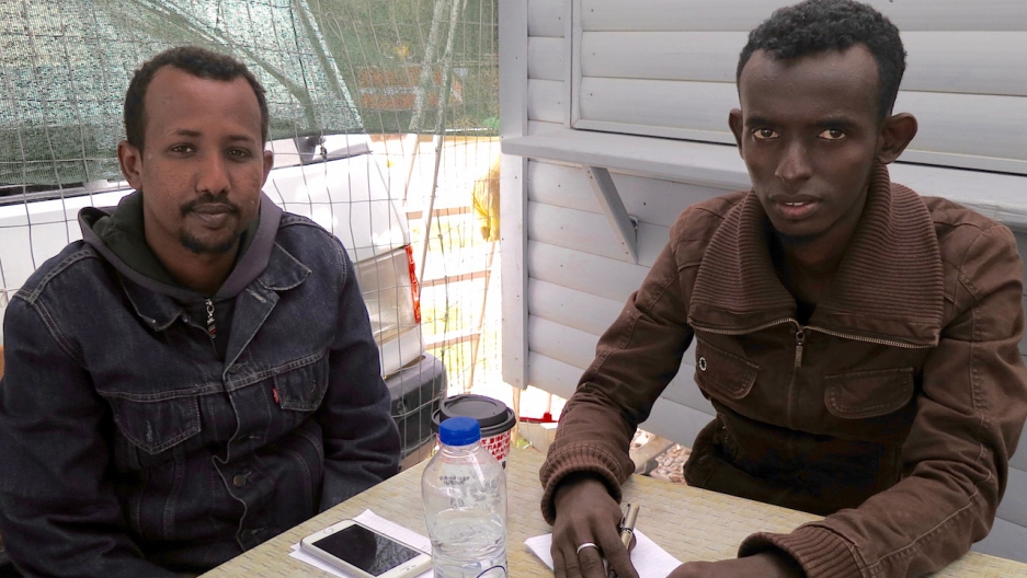 Somali journalists Kamal Hassan and Yassin Abuukar sit at a canteen outside Moria refugee camp in Lesbos, Greece. Credit: Jeanne Carstensen
