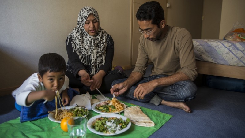Ali Jaffari and his wife, Wajiha, and son Shayan, 4, eat dinner in their room while their other son naps. Together they traveled from Afghanistan to Greece, hoping to make their way to Germany. Now they are stuck in Greece. Credit: Jodi Hilton/Pulitzer Center on Crisis Reporting. Used with permission.