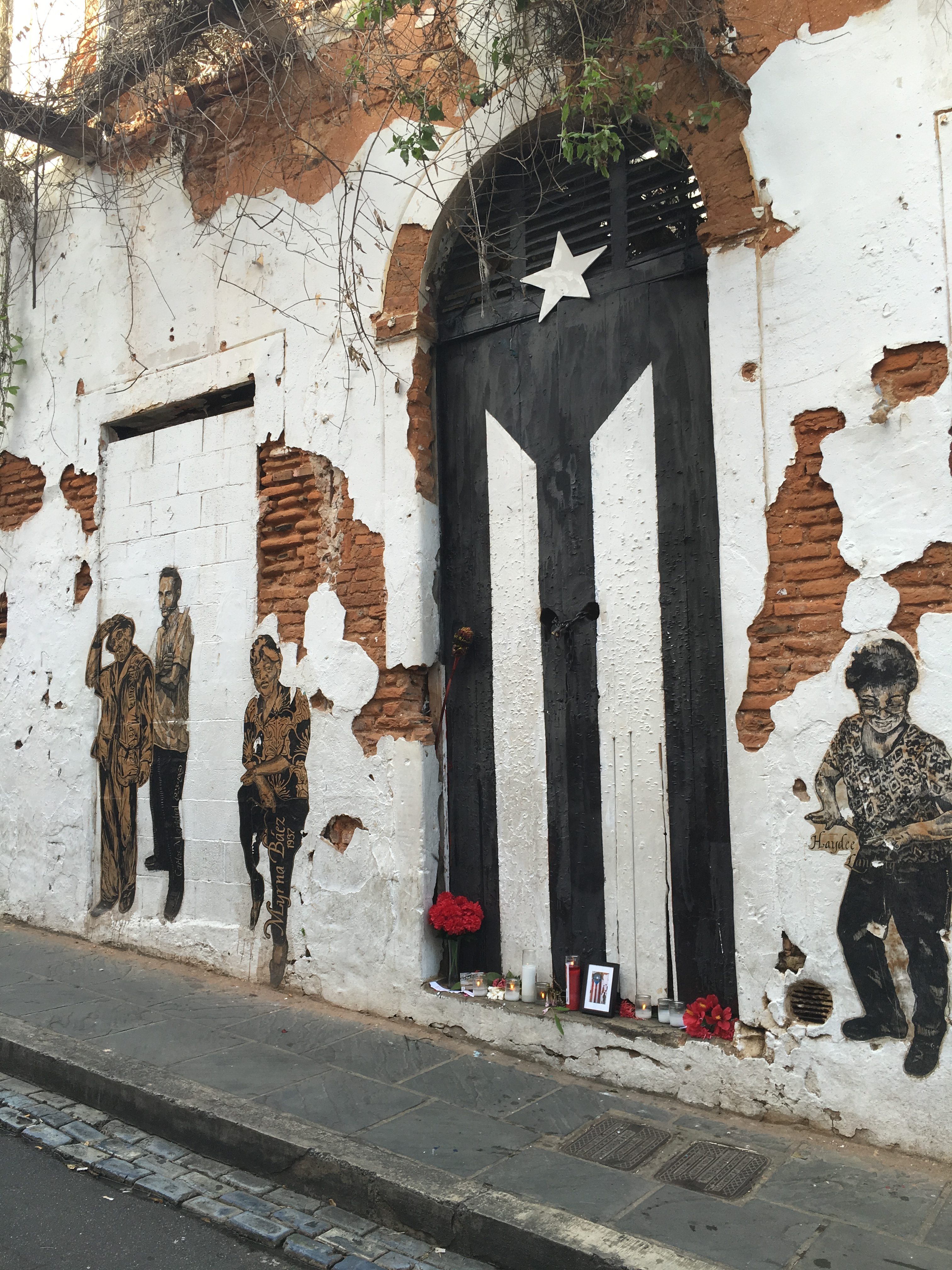 The famous door in Old San Juan now has the Puerto Rican flag painted in black and white, as a sign of mourning and resistance. There is also a small altar. Photo by Marina I. Pineda Shokooh, used with permission. 