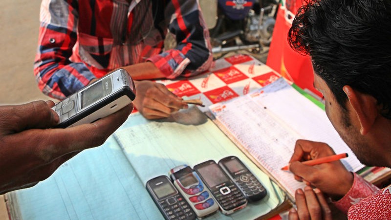 A mobile phone retailer in Bangladesh loads a customer’s mobile phone with credit. Image by Shafiqul Alam. Copyright Demotix (18/1/2013)