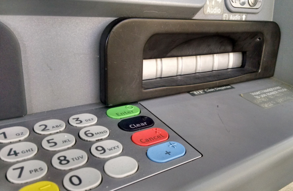 A closeup of the tiny pinhole that allows a mini spy camera embedded in the fake cash dispenser bezel to record customers entering their PINs.